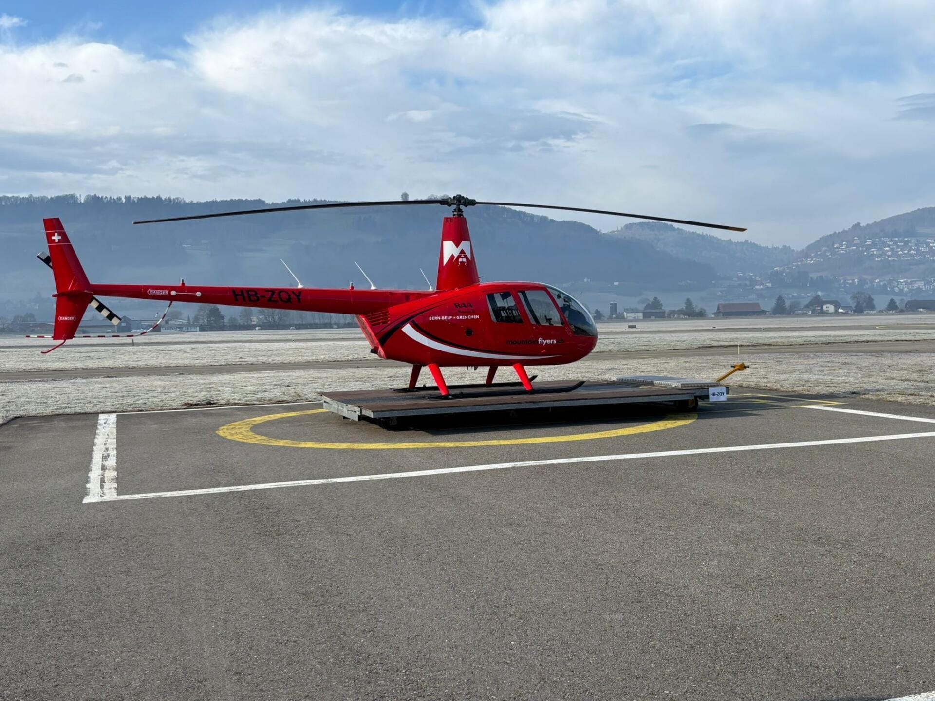 Robinson R44 Raven II, Callsign HB-ZQY der Mountainflyers AG auf der Plattform, startbereit auf dem Flughafen Bern-Belp (LSZB)