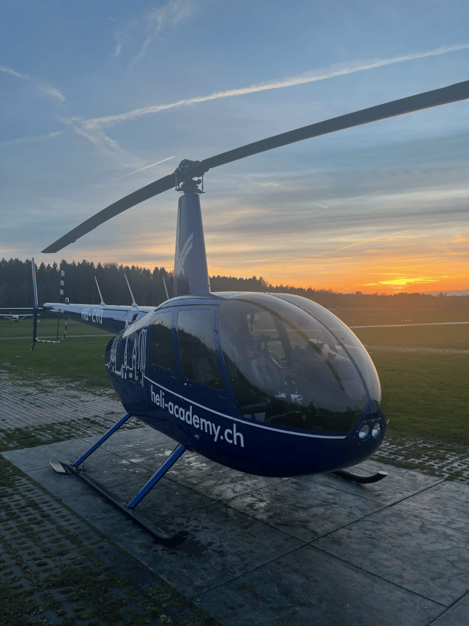 Robinson R44 Raven II von vorne auf dem Helipad im Sonnenuntergang
