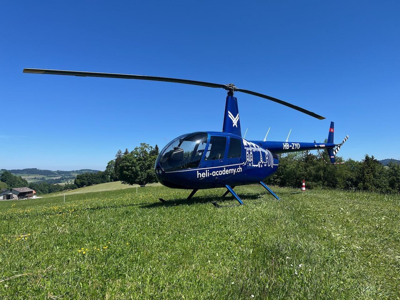 Robinson R44 Raven II auf einer Wiese von schräg vorne