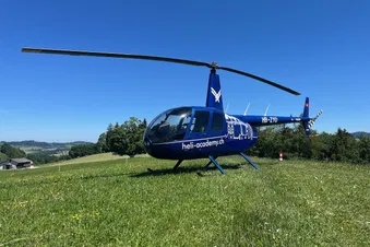 Robinson R44 Raven II auf einer Wiese von schräg vorne