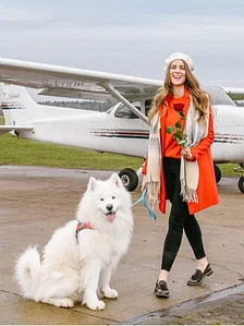 Frau mit Hund vor Flugzeug