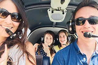 Four smiling people in the cockpit of a light aircraft