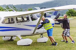 Three people push a light aircraft