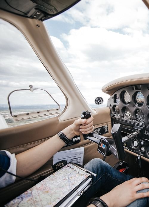 A pilot flies a light aircraft with a map on his lap