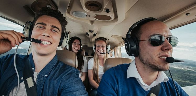 Quatre personnes souriantes dans le cockpit d'un avion léger